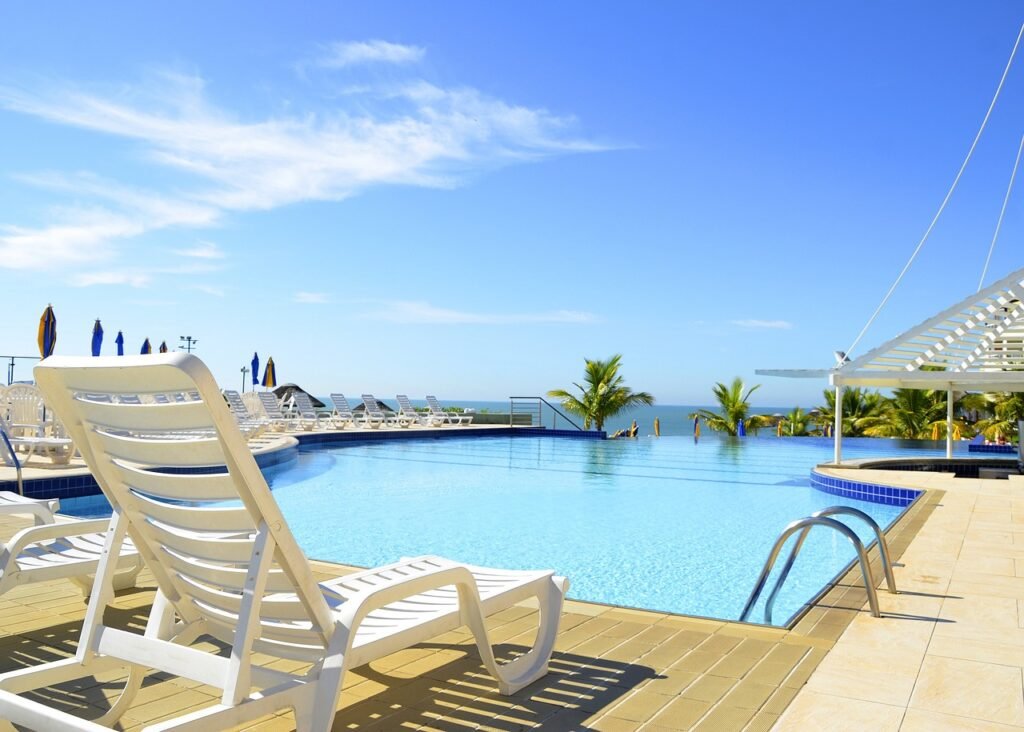 Pontos turísticos imperdíveis no Rio de Janeiro em 2024 3 Foto de piscina de hotel, cadeira de praia a beira da piscina, ao fundo as águas do mar.