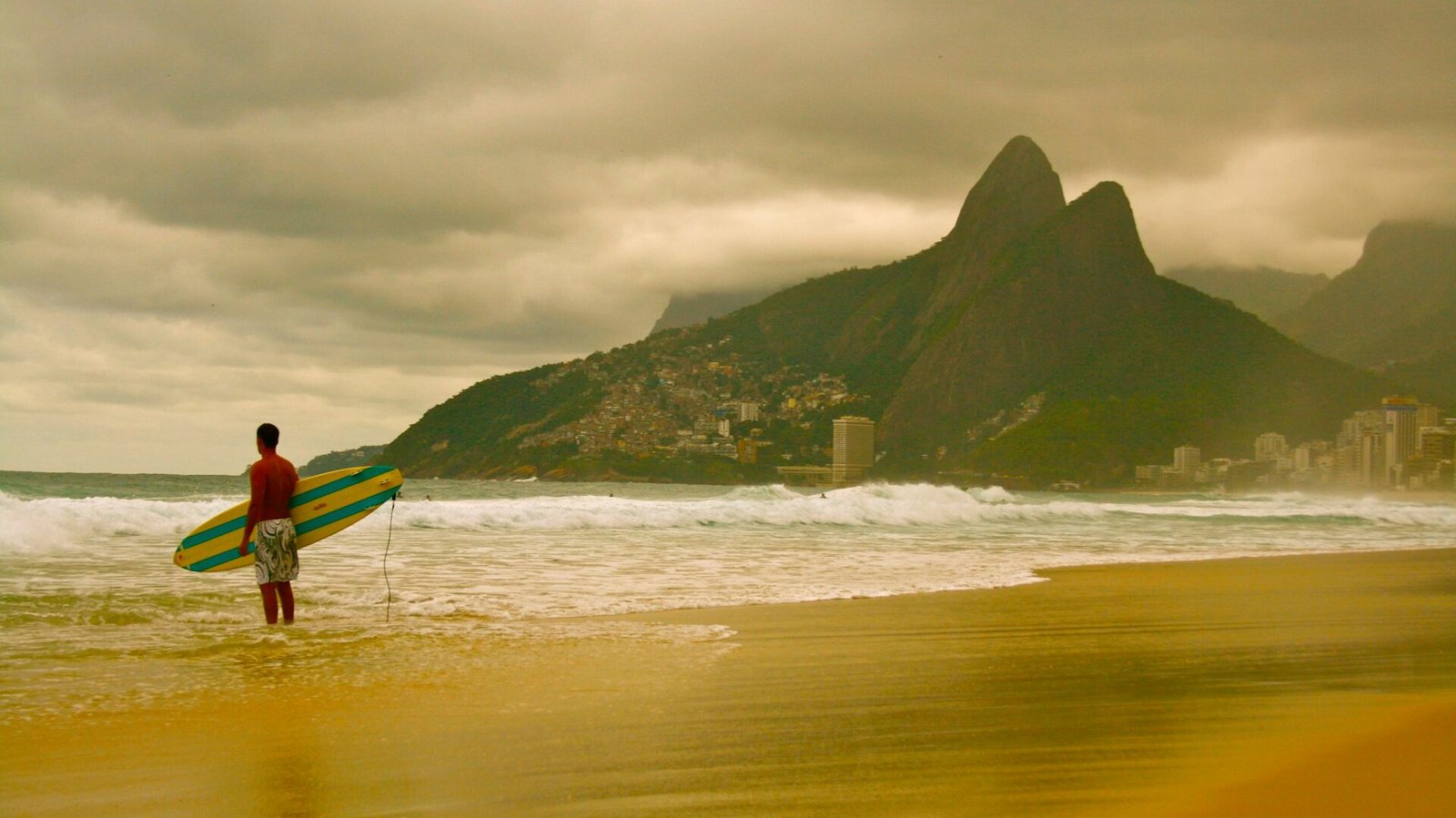 Praia de Ipanema: A musa inspiradora do Rio de Janeiro 1 Foto praia de Ipanema, fim de tarde, céu nublado. Surfista segurando prancha olhando as ondas.