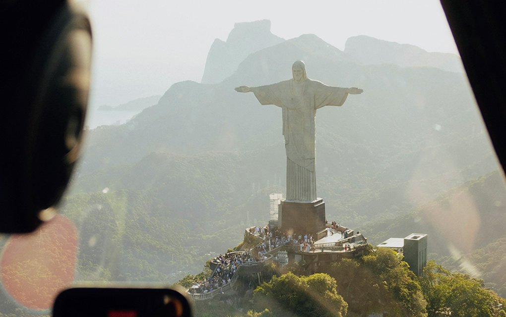 Visite o Cristo Redentor em 2024: Informações, Ingressos e Dicas 1 Pessoa em voo panorâmico com celular tirando foro do Cristo Redentor.