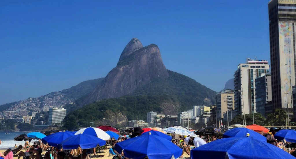 Praia do Leblon, Rio de Janeiro: Um Guia Completo 1 Foto da praia do Leblon no Rio de Janeiro, guarda-sois azuis armados na areia da praia.