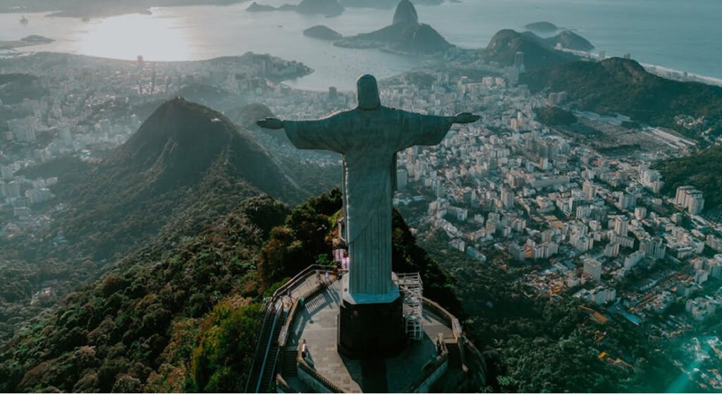 Tudo Sobre o Réveillon 2025 no Cristo Redentor: Pacotes, Atrações e Acessos 1 Cristo Redentor visto de cima, dia claro. A frente da estátua está a cidade do Rio de Janeiro.