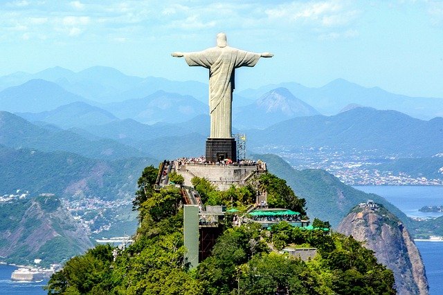 Cristo Redentor: O que você precisa saber antes de ir 2 Imagem do Cristo, pessoas visitando, Rio de Janeiro ao fundo. Dia de Sol.