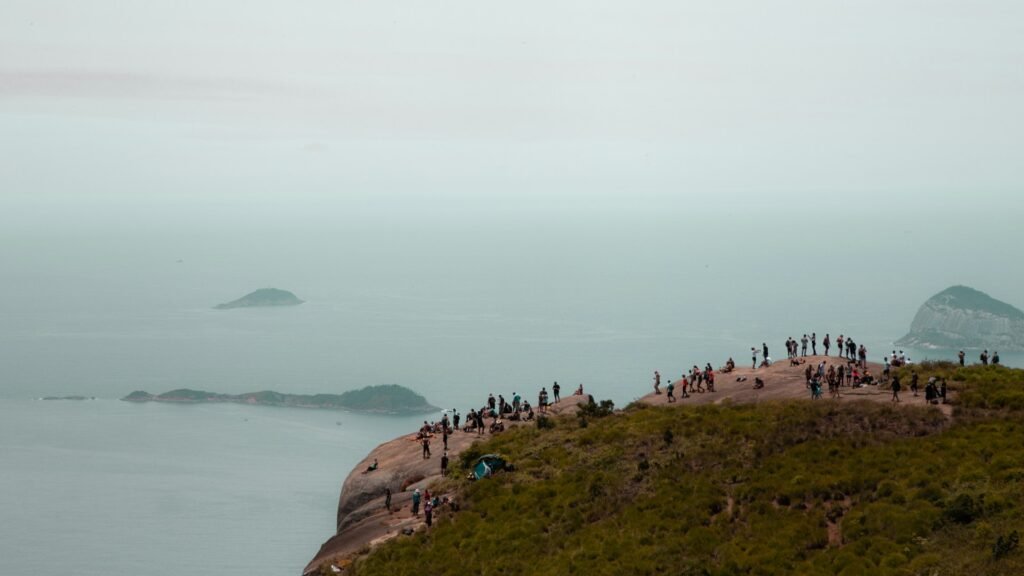 A Pedra da Gávea: Uma Aventura Imperdível no Rio de Janeiro 3 Pessoas sob a pedra da Gávea no Rio. Dia nublado.