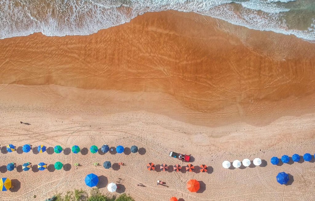 Praia de Geribá em Búzios: Onde Ficar e o que Fazer 1 Foto tirada por drone da praia de Geribá em Búzios, guarda-sois na areia da praia.