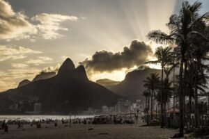 HOSPEDAGENS 7 Vista aérea da Praia da Prainha no Rio de Janeiro, com mar azul e morros cobertos de mata